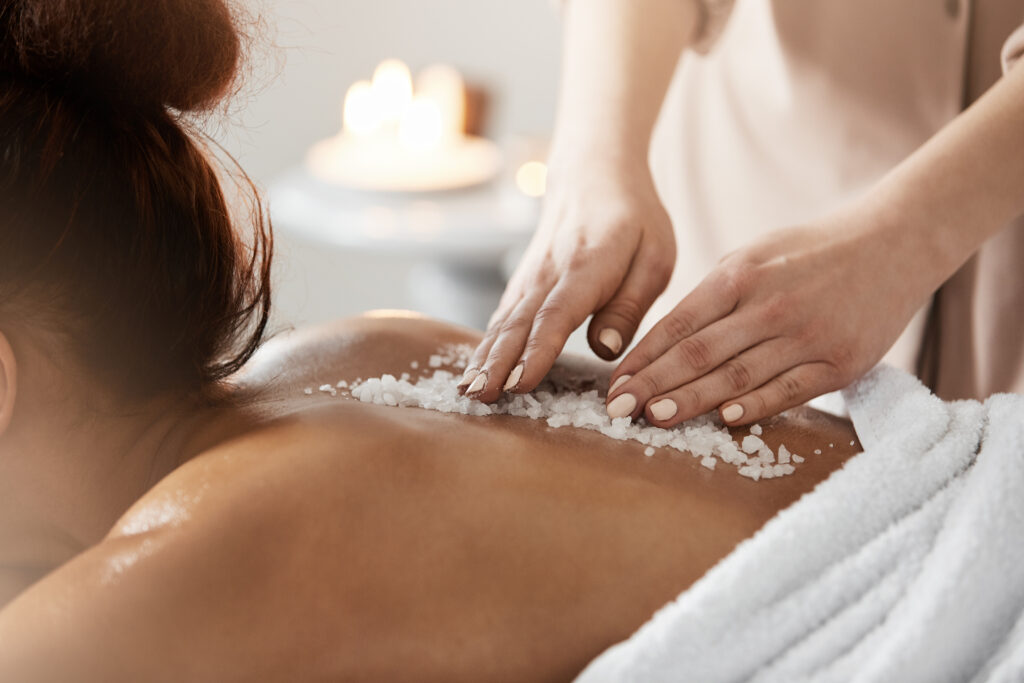 Close up photo of young beautiful african girl relaxing enjoying spa health massage with sea salt.